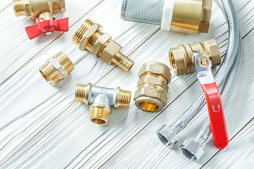 plumbing tools brass fixtures fittings on white wood board