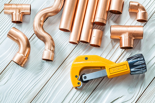 close up view copper pipes and fittings pipecutter on white boards