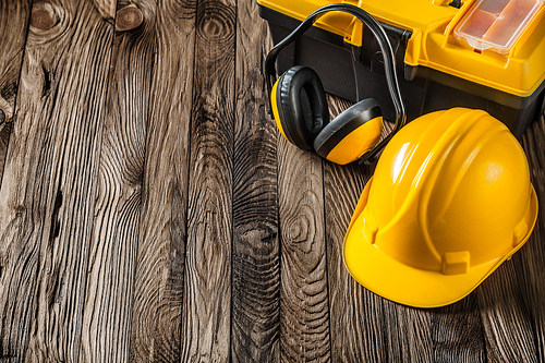 construction tools yellow helmet earphones and toolbox on vintage wood