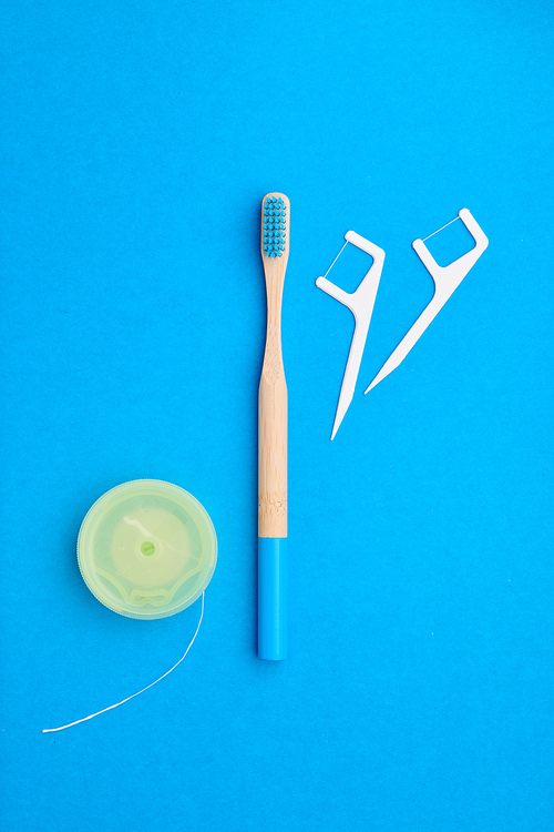 Toothbrushes and oral care tools over blue background top view copy space flat lay. Tooth care, dental hygiene and health concept.