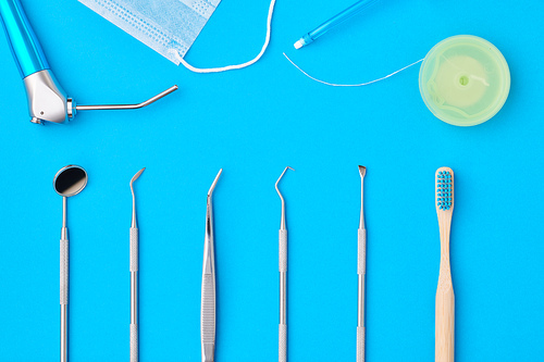 Dentist tools over blue background top view flat lay. Tooth care, dental hygiene and health concept.