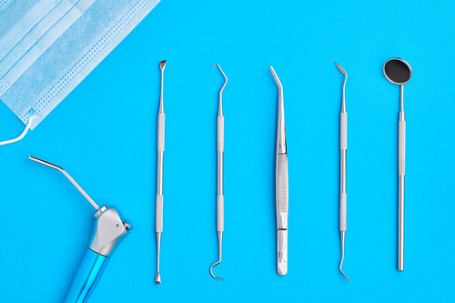 Dentist tools over blue background top view flat lay. Tooth care, dental hygiene and health concept.