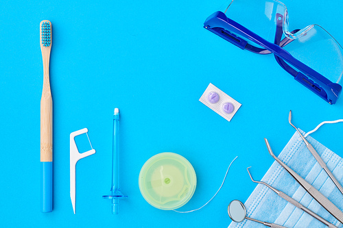 Dentist tools over blue background top view flat lay. Tooth care, dental hygiene and health concept.