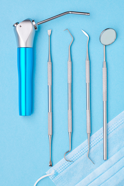 Dentist tools over light blue background top view flat lay. Tooth care, dental hygiene and health concept.