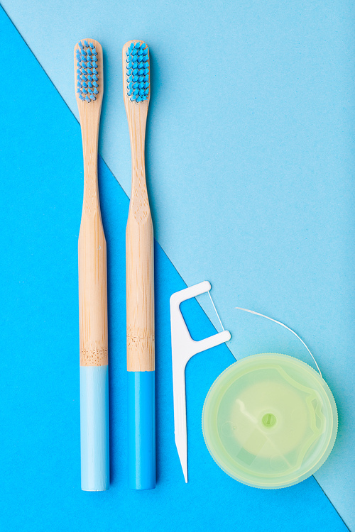 Toothbrushes and oral care tools over blue background top view copy space flat lay. Tooth care, dental hygiene and health concept.