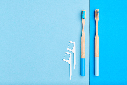 Toothbrushes and oral care tools over blue background top view copy space flat lay. Tooth care, dental hygiene and health concept.