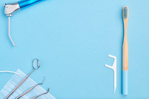 Dentist tools over light blue background top view copy space flat lay. Tooth care, dental hygiene and health concept.