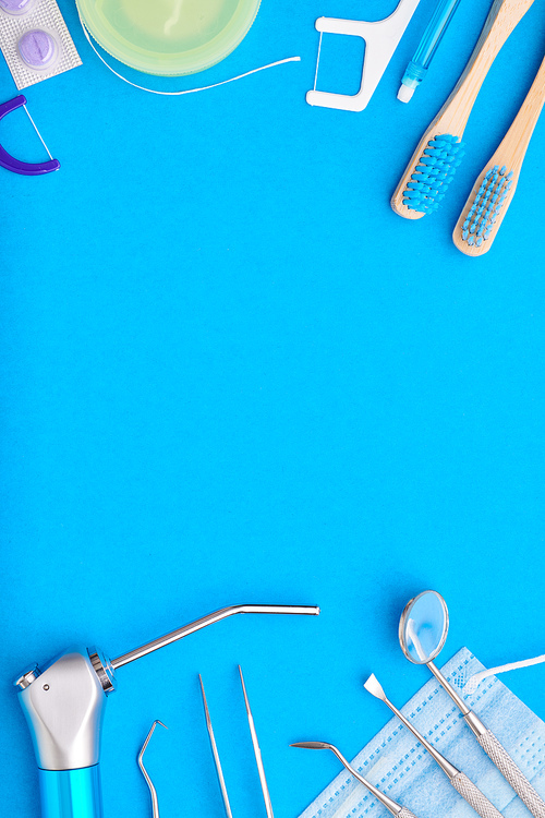 Dentist tools over blue background top view copy space flat lay. Tooth care, dental hygiene and health concept.