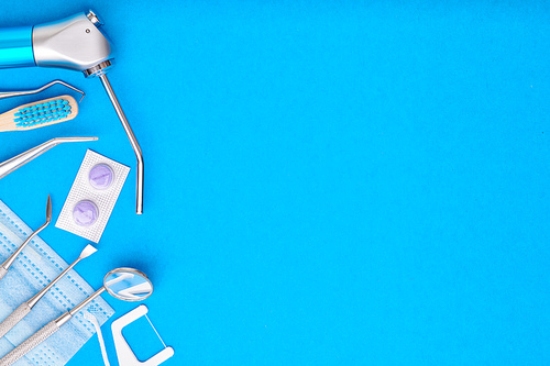 Dentist tools over blue background top view copy space flat lay. Tooth care, dental hygiene and health concept.