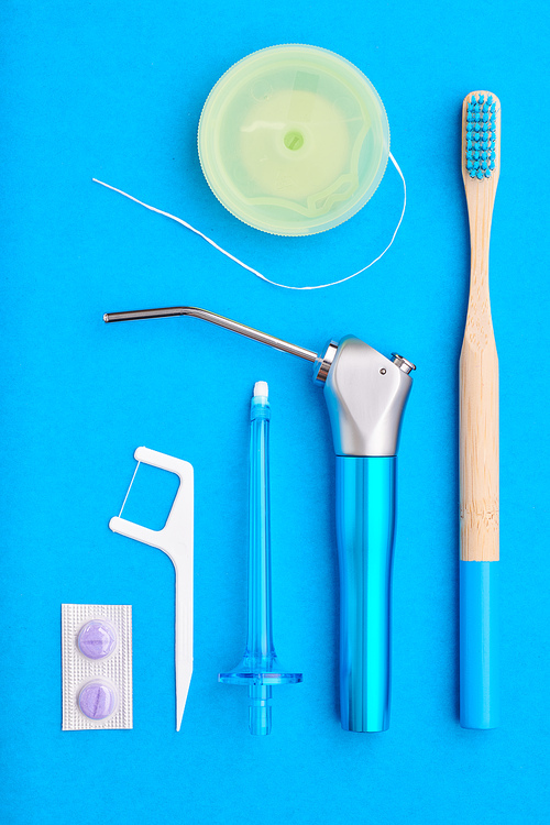 Toothbrushes and oral care tools over blue background top view copy space flat lay. Tooth care, dental hygiene and health concept.