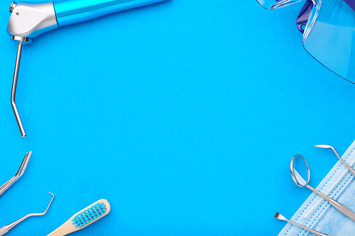 Dentist tools over blue background top view copy space flat lay. Tooth care, dental hygiene and health concept.