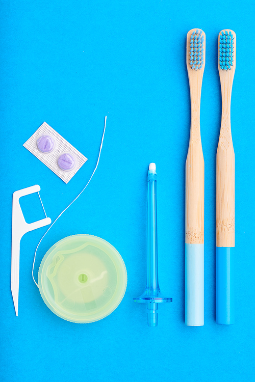 Toothbrushes and oral care tools over blue background top view copy space flat lay. Tooth care, dental hygiene and health concept.