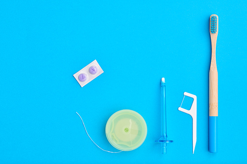 Toothbrushes and oral care tools over blue background top view copy space flat lay. Tooth care, dental hygiene and health concept.