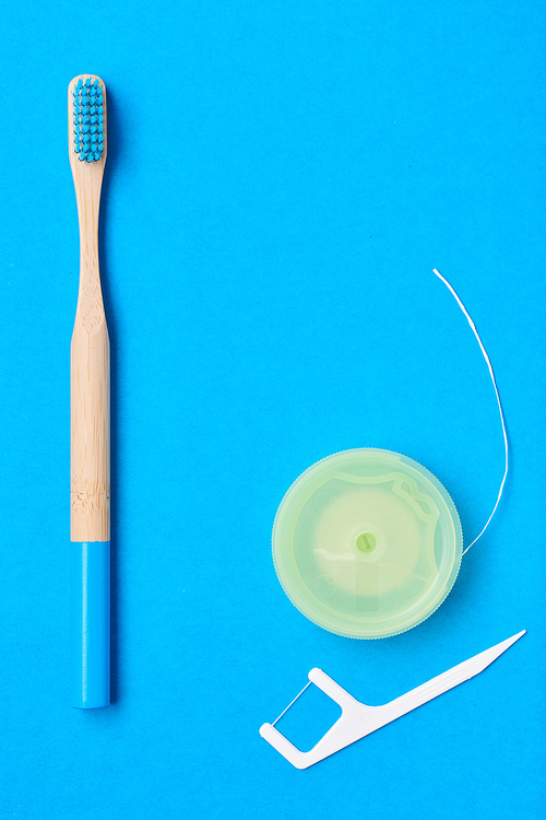 Toothbrushes and oral care tools over blue background top view copy space flat lay. Tooth care, dental hygiene and health concept.