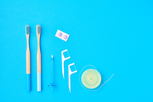 Toothbrushes and oral care tools over blue background top view copy space flat lay. Tooth care, dental hygiene and health concept.