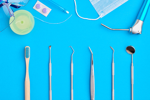 Dentist tools over blue background top view flat lay. Tooth care, dental hygiene and health concept.