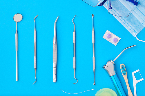 Dentist tools over blue background top view flat lay. Tooth care, dental hygiene and health concept.