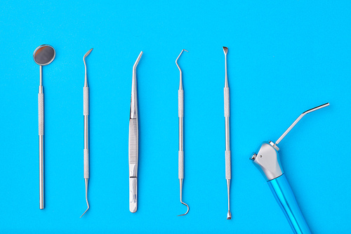 Dentist tools over blue background top view flat lay. Tooth care, dental hygiene and health concept.