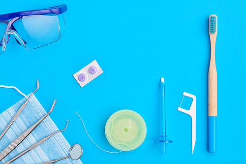 Dentist tools over blue background top view flat lay. Tooth care, dental hygiene and health concept.