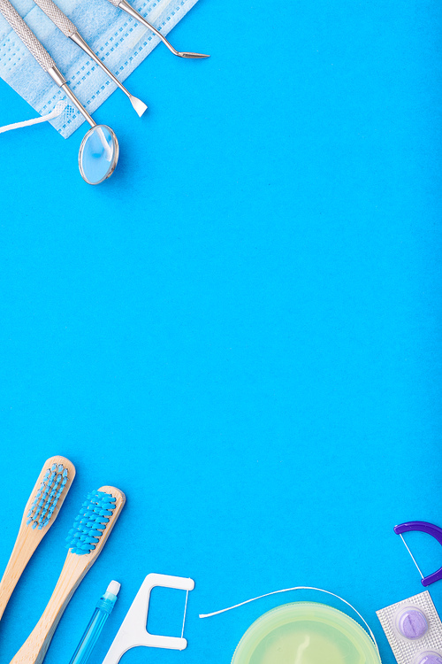 Dentist tools over blue background top view copy space flat lay. Tooth care, dental hygiene and health concept.