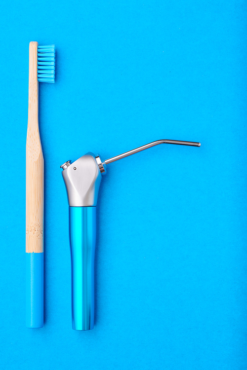 Toothbrushes and oral care tools over blue background top view copy space flat lay. Tooth care, dental hygiene and health concept.