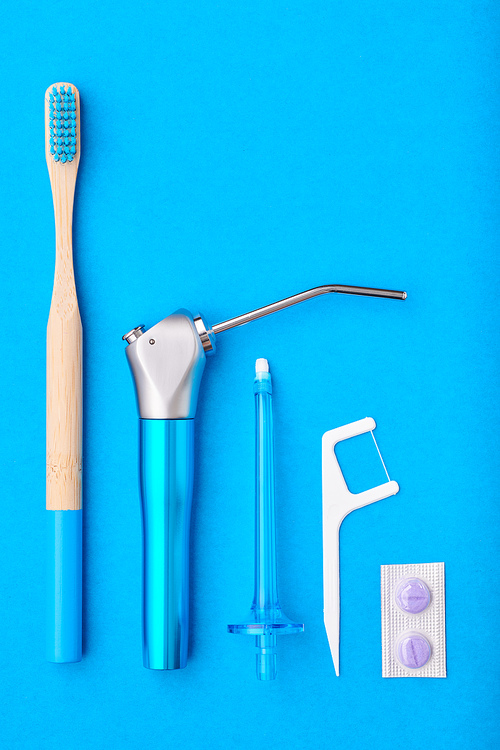 Toothbrushes and oral care tools over blue background top view copy space flat lay. Tooth care, dental hygiene and health concept.