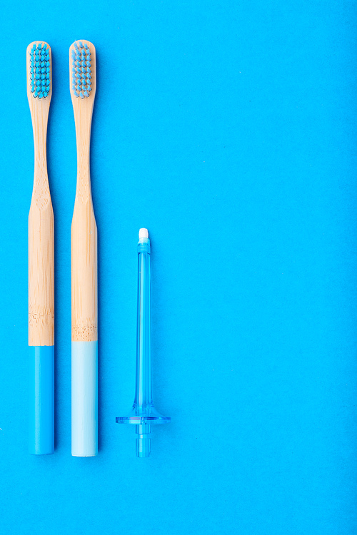 Toothbrushes and oral care tools over blue background top view copy space flat lay. Tooth care, dental hygiene and health concept.