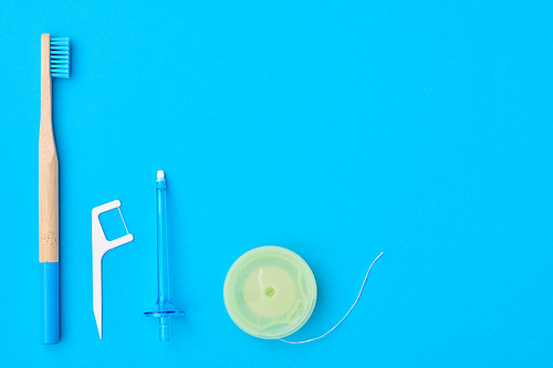 Toothbrushes and oral care tools over blue background top view copy space flat lay. Tooth care, dental hygiene and health concept.