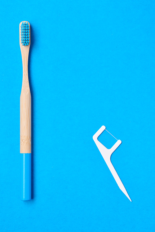 Toothbrushes and oral care tools over blue background top view copy space flat lay. Tooth care, dental hygiene and health concept.