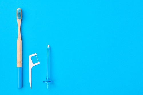 Toothbrushes and oral care tools over blue background top view copy space flat lay. Tooth care, dental hygiene and health concept.