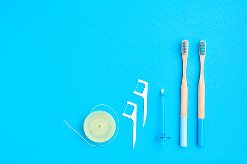 Toothbrushes and oral care tools over blue background top view copy space flat lay. Tooth care, dental hygiene and health concept.