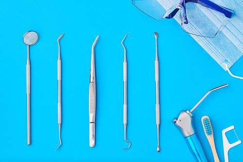 Dentist tools over blue background top view flat lay. Tooth care, dental hygiene and health concept.