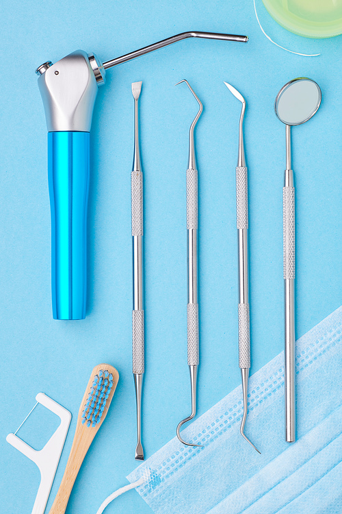 Dentist tools over light blue background top view flat lay. Tooth care, dental hygiene and health concept.