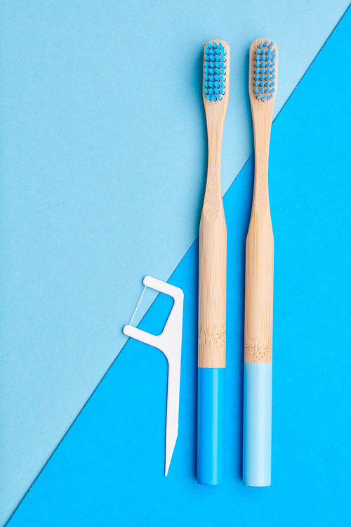 Toothbrushes and oral care tools over blue background top view copy space flat lay. Tooth care, dental hygiene and health concept.