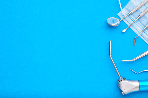 Dentist tools over blue background top view copy space flat lay. Tooth care, dental hygiene and health concept.