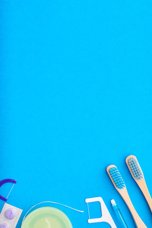 Toothbrushes and oral care tools over blue background top view copy space flat lay. Tooth care, dental hygiene and health concept.