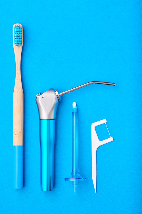 Toothbrushes and oral care tools over blue background top view copy space flat lay. Tooth care, dental hygiene and health concept.