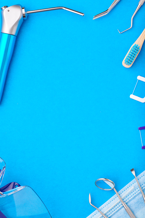 Dentist tools over blue background top view copy space flat lay. Tooth care, dental hygiene and health concept.