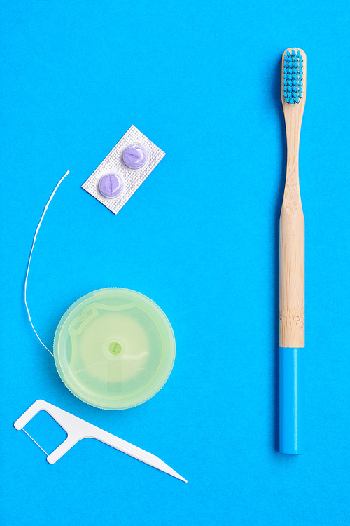 Toothbrushes and oral care tools over blue background top view copy space flat lay. Tooth care, dental hygiene and health concept.