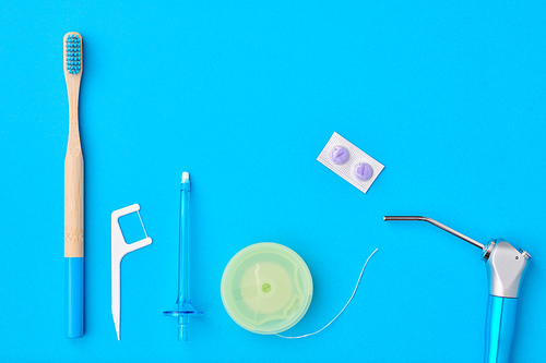 Toothbrushes and oral care tools over blue background top view copy space flat lay. Tooth care, dental hygiene and health concept.