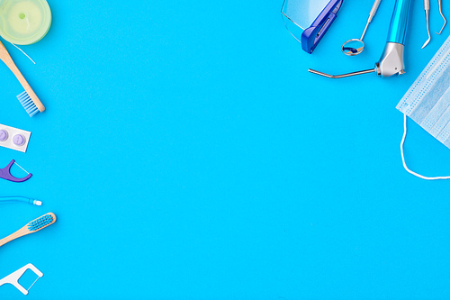 Dentist tools over blue background top view copy space flat lay. Tooth care, dental hygiene and health concept.