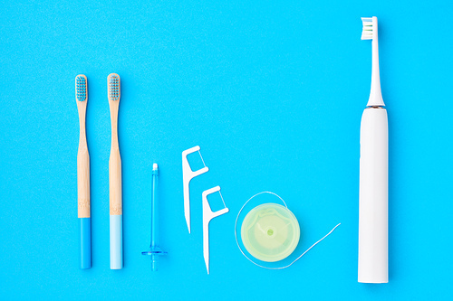 Toothbrushes and oral care tools over blue background top view copy space flat lay. Tooth care, dental hygiene and health concept.