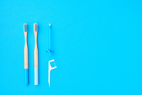 Toothbrushes and oral care tools over blue background top view copy space flat lay. Tooth care, dental hygiene and health concept.