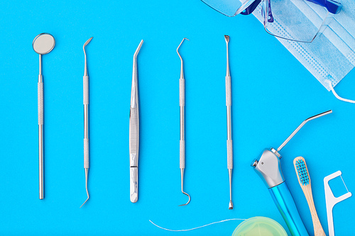 Dentist tools over blue background top view flat lay. Tooth care, dental hygiene and health concept.