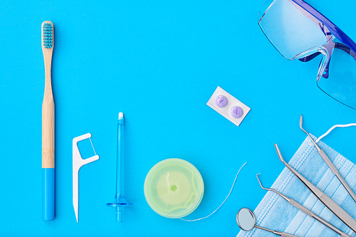 Dentist tools over blue background top view flat lay. Tooth care, dental hygiene and health concept.