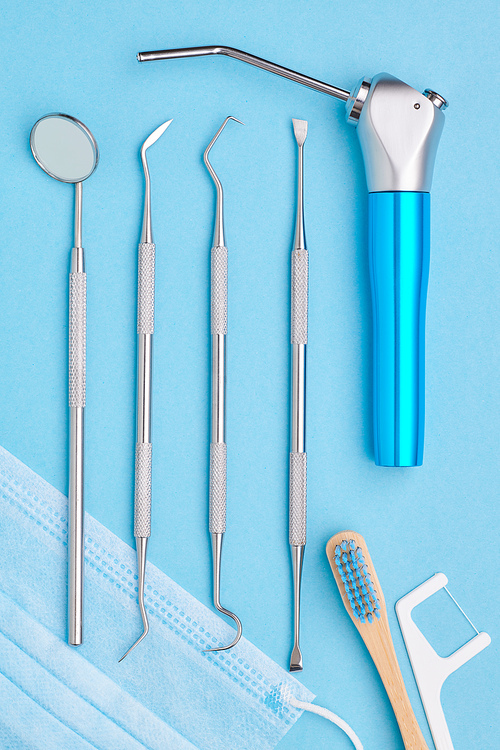 Dentist tools over light blue background top view flat lay. Tooth care, dental hygiene and health concept.