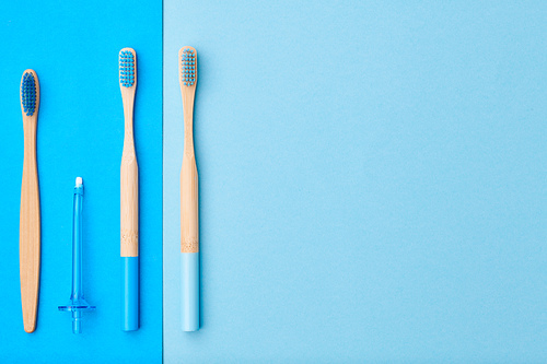 Toothbrushes and oral care tools over blue background top view copy space flat lay. Tooth care, dental hygiene and health concept.