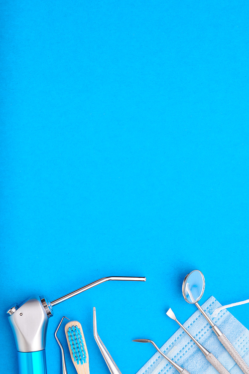 Dentist tools over blue background top view copy space flat lay. Tooth care, dental hygiene and health concept.