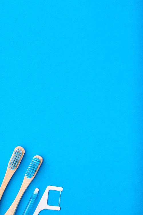 Toothbrushes and oral care tools over blue background top view copy space flat lay. Tooth care, dental hygiene and health concept.