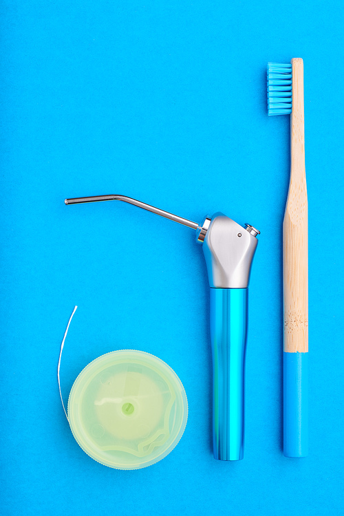 Toothbrushes and oral care tools over blue background top view copy space flat lay. Tooth care, dental hygiene and health concept.